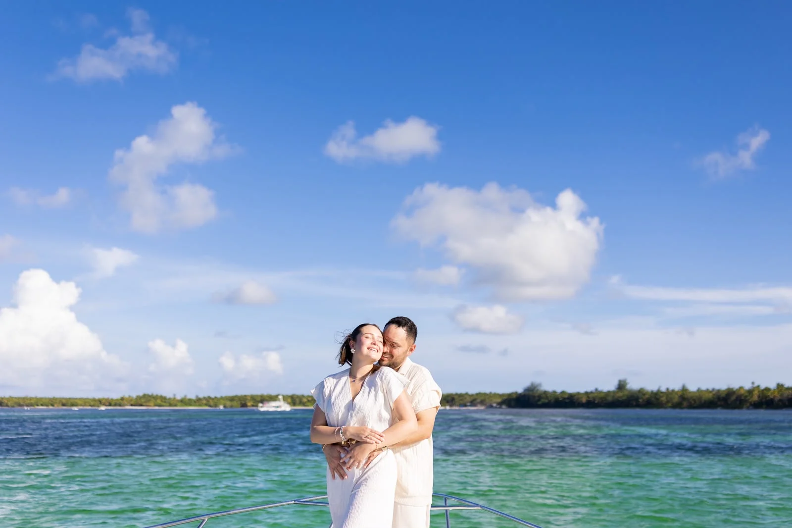 Couple embracing on the yacht with turquoise water behind them